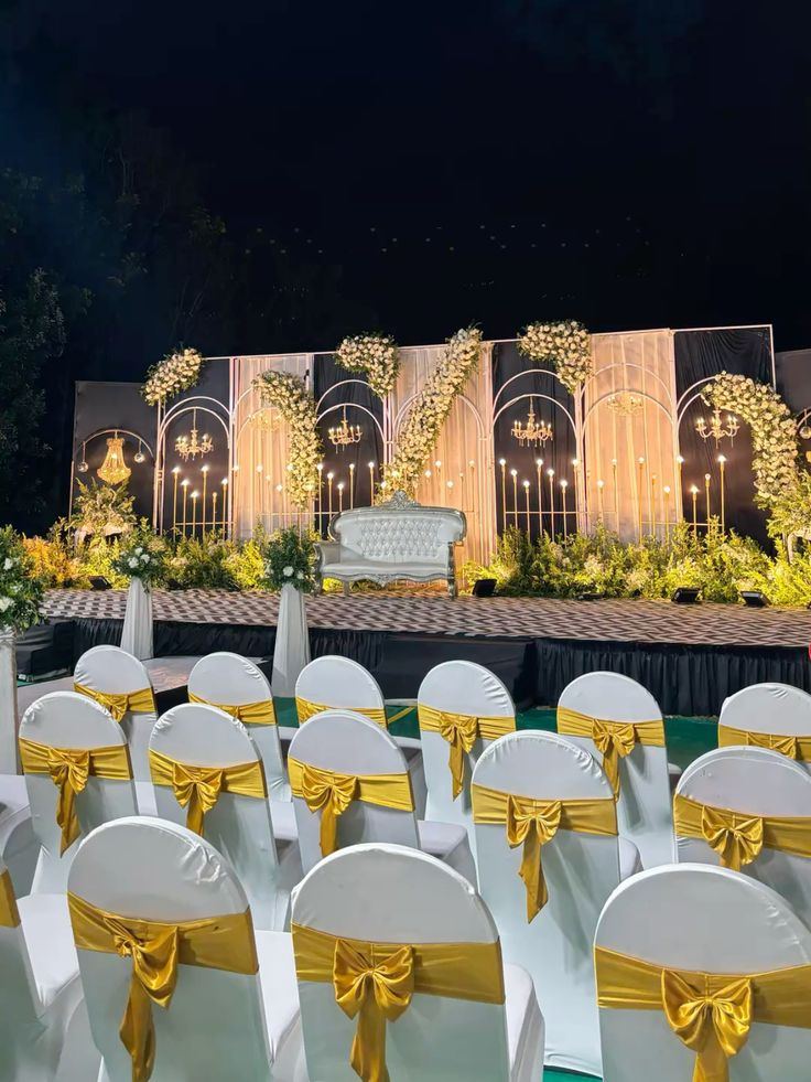 Elegant black and gold Sangeet stage with chandeliers and floral drapes